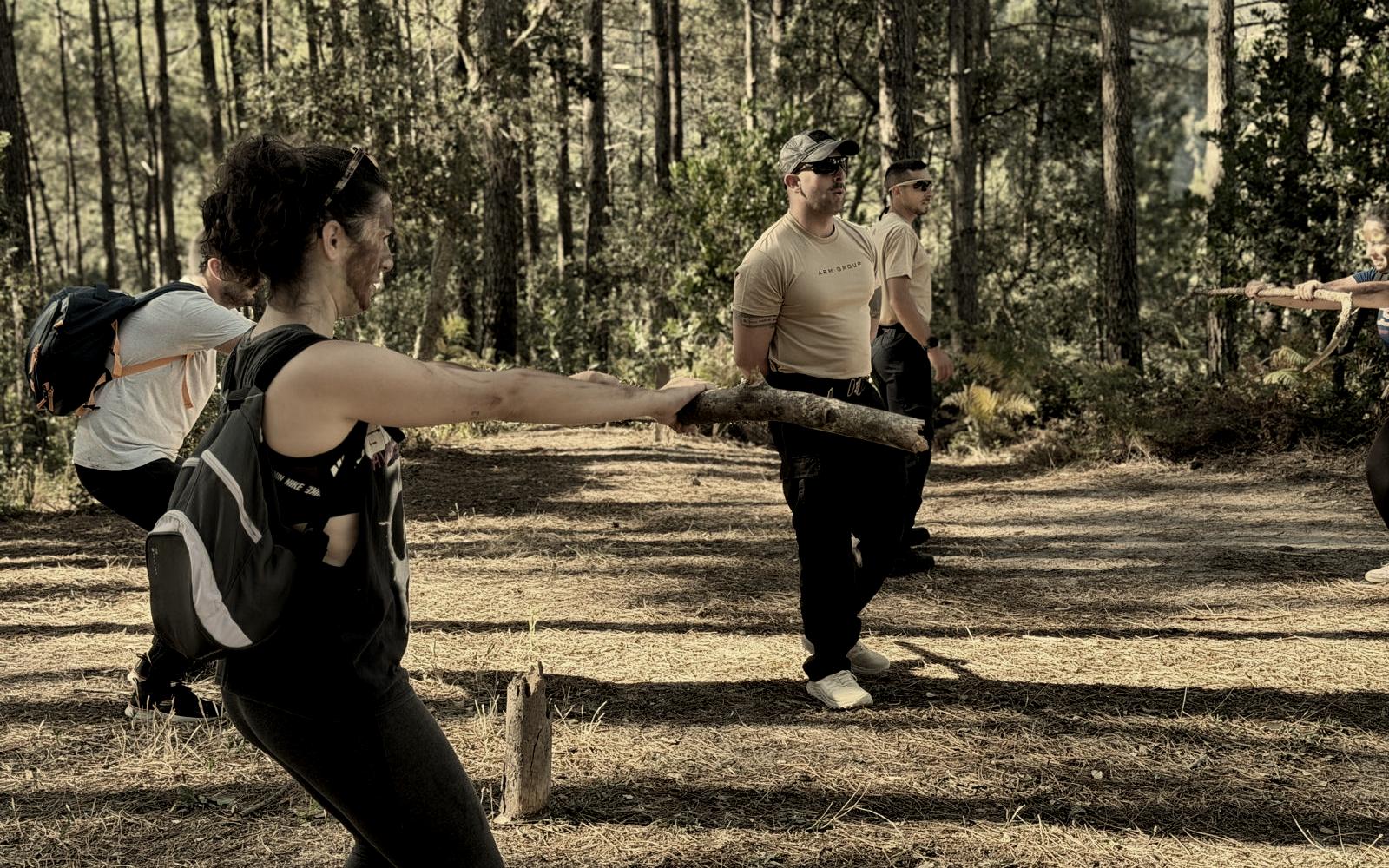 Equipa a puxar um tronco em conjunto, num exercício de cooperação